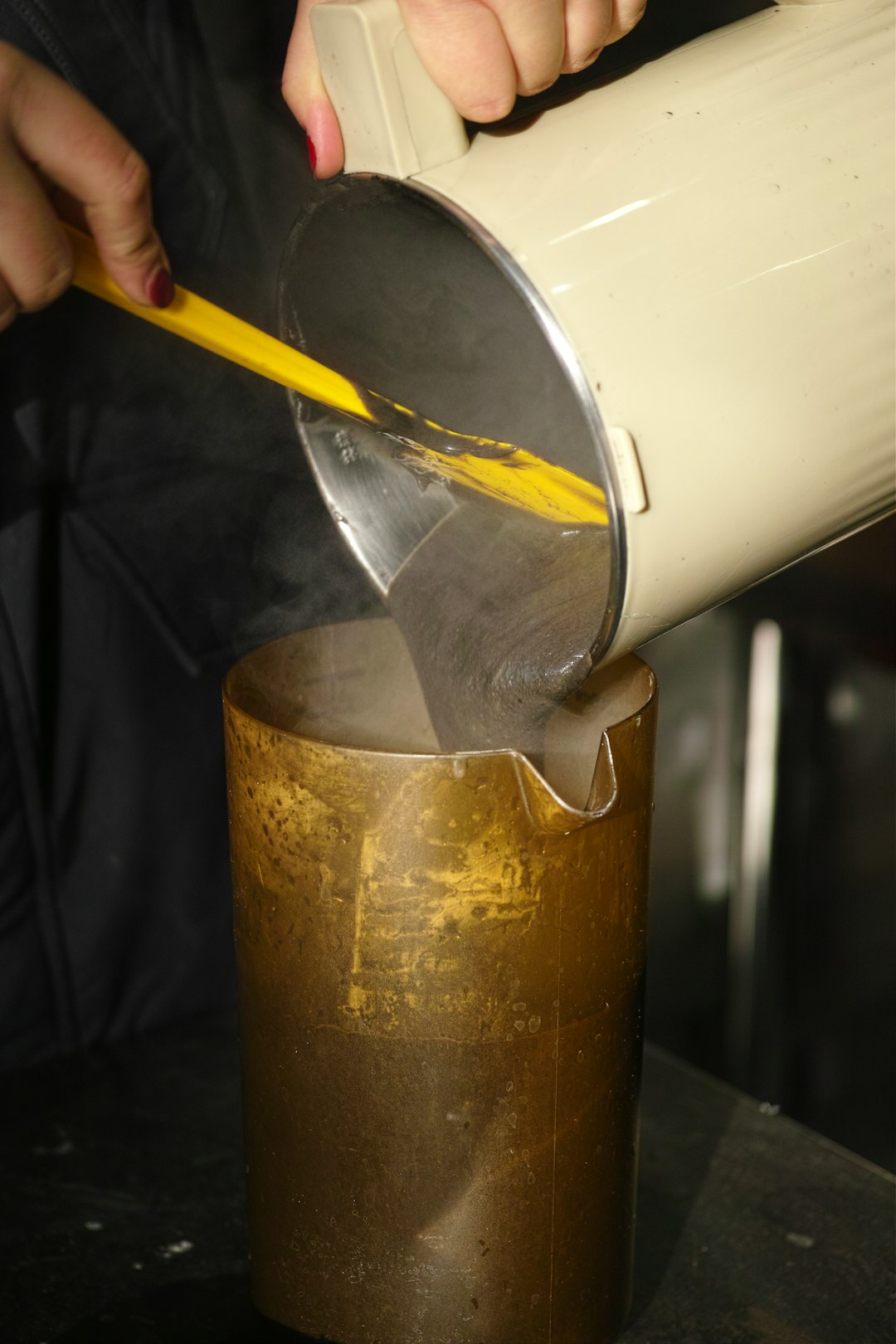 pouring-hot-liquid-from-a-pitcher-into-a-metal-cup-yfk3aavtatw