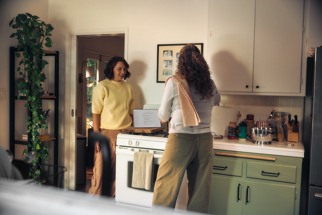 two-women-talking-in-a-kitchen-while-cooking-3c-k7h8yghw